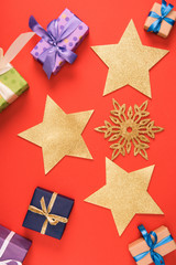 top view of golden stars, decorative snowflake and christmas presents on red