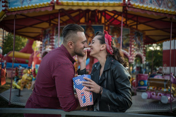 young cute  couple in amusement  park smiling and eating pop corns 