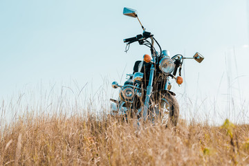 retro motorbike on rural meadow against blue sky
