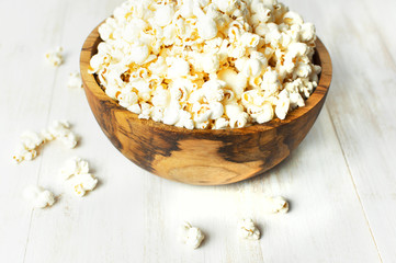 Brown wooden bowl with delicious traditional popcorn on a light wooden background. Top view of a...
