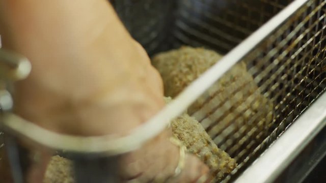 Woman putting food in a deep fryer in slow motion