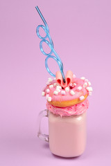 Pink strawberry freakshake with marshmallow and sweets.