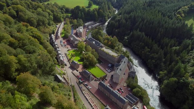 Aerial footage over the village of New Lanark. A World Heritage Site in a deep valley next to the River Clyde.