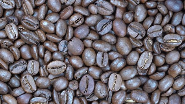 Fried coffee beans background, close up, rotation loopable 4k top view. Food  background. Gastronomy concept, organic food. Macro coffee beans
