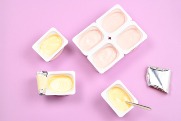 Plastic cup with tasty yogurt on lilac background. Top view. Space for text or design.