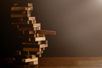 business man try to build wood block on wooden table and black background business organization startup concept