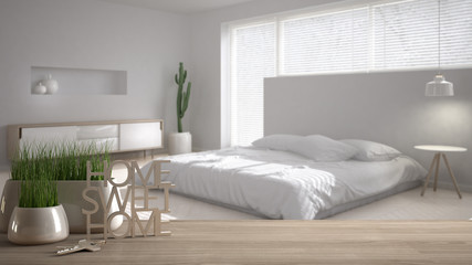 Fototapeta na wymiar Wooden table, desk or shelf with potted grass plant, house keys and 3D letters making the words home sweet home, over modern white bedroom, interior design, blur background