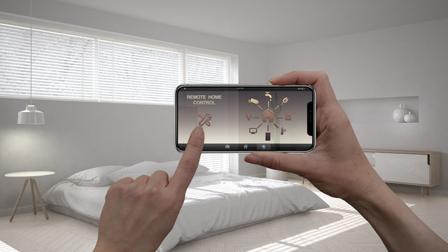 Remote home control system on a digital smart phone tablet. Device with app icons. Interior of minimalist bedroom in the background, architecture design