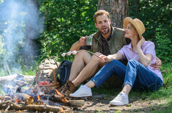 Hike picnic. Couple eat snacks and drink. Couple friends prepare roasted marshmallows snack nature background. Couple in love camping forest roasting marshmallows. Roasting marshmallows at bonfire