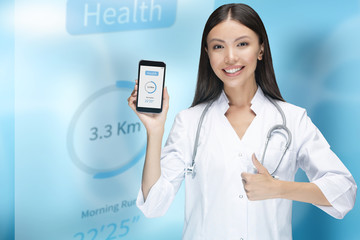 Phone medical application concept. A woman doctor is giving a thumbs up and holding up a phone...