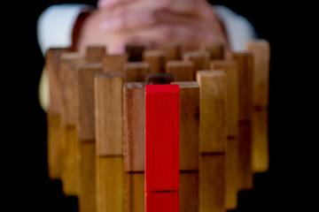 business Man hand pick one red wooden block from others wood block in row metaphor to leadership ideas concept
