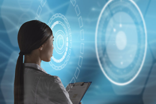 Abstract health care and medical engineering concept. A woman health care professional, or scientist, or bio engineer, is using a futuristic, innovative technology holographic machine 