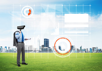 Camera headed man standing on green grass against modern cityscape