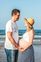 Young pregnant couple in the beach