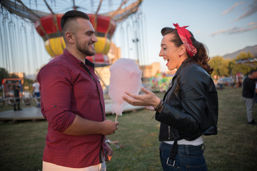 Fototapeta na wymiar young man surprised girlfriend with cotton candy in amusement park 