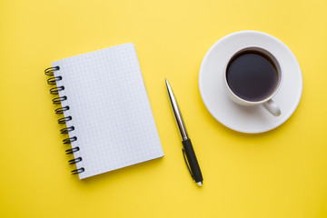 Notepad for text and Cup of coffee yellow table with copy space. Education and office concept.