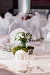 Fototapeta premium Beautiful and exquisite decoration of the wedding celebration. Flower arrangement of white flowers and blueberry greens, in a glass ball vase