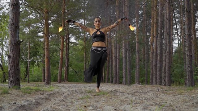 Beautiful woman does fire show in the forest
