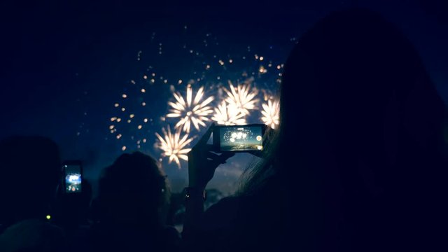 People are shooting fireworks display with their phones. Smartphone shooting fireworks.