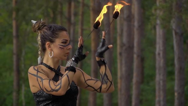 Beautiful woman does fire show in the forest