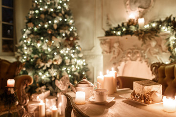 Christmas tree, garlands, candles,lanterns, gifts in the evening. classical interior of a white room with a decorated fireplace, sofa,