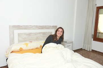 Obraz premium Happy woman smiling on bed after alarm sound
