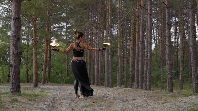 Woman in the forest is dancing with fire bowls