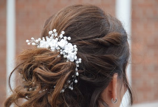 Kunstvolle, hochgesteckte Frisur einer Braut mit wei&szlig;en Haarspangen