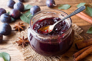 Plum jam in a glass jar. Fresh plum fruit on a wooden table. - obrazy, fototapety, plakaty