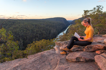 A woman sitting on a rock reading in nature