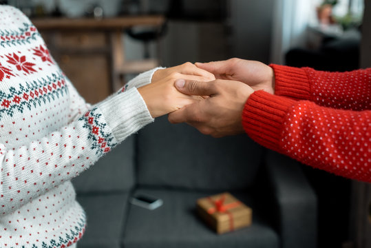 cropped image of man holding hands and leading girlfriend for making surprise on christmas at home