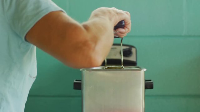 Woman removing food from a deep fryer
