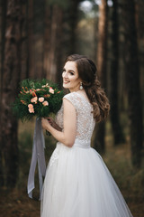 Fototapeta na wymiar Beautiful bride in fashion wedding dress on natural background.The stunning young bride is incredibly happy. Wedding day. .A beautiful bride portrait in the forest.