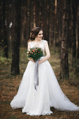 Fototapeta na wymiar Beautiful bride in fashion wedding dress on natural background.The stunning young bride is incredibly happy. Wedding day. .A beautiful bride portrait in the forest.