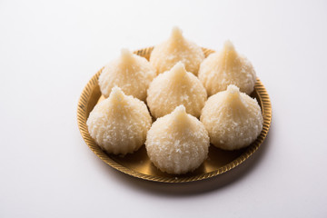 Sweet Modak made using coconut, khoya and sugar. Popular Maharashtrian recipe offered to lord Ganesha in Ganesh Festival. Served in a plate. Selective focus