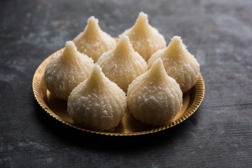 Sweet Modak made using coconut, khoya and sugar. Popular Maharashtrian recipe offered to lord Ganesha in Ganesh Festival. Served in a plate. Selective focus