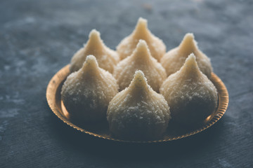 Sweet Modak made using coconut, khoya and sugar. Popular Maharashtrian recipe offered to lord Ganesha in Ganesh Festival. Served in a plate. Selective focus