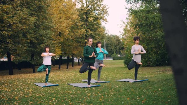 Beautiful girls in sportswear are practising yoga doing variations of Tree position then moving into Chair pose Utkatasana. Young people and recreation concept.
