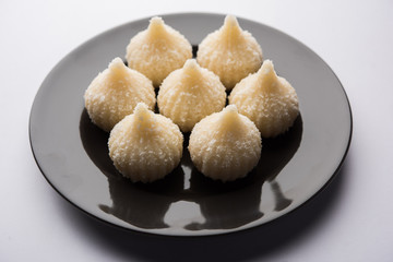 Sweet Modak made using coconut, khoya and sugar. Popular Maharashtrian recipe offered to lord Ganesha in Ganesh Festival. Served in a plate. Selective focus