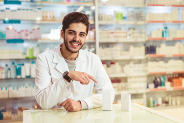 Fototapeta premium Friendly male pharmacist dispensing medicine holding a box of tablets