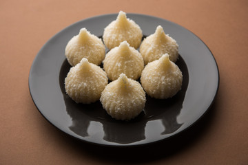 Sweet Modak made using coconut, khoya and sugar. Popular Maharashtrian recipe offered to lord Ganesha in Ganesh Festival. Served in a plate. Selective focus
