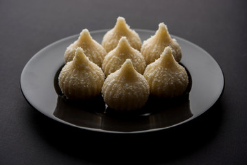 Sweet Modak made using coconut, khoya and sugar. Popular Maharashtrian recipe offered to lord Ganesha in Ganesh Festival. Served in a plate. Selective focus
