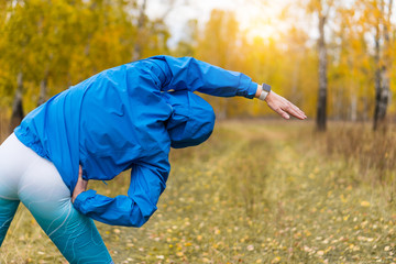 An athlete in an autumn park does fitness exercises.