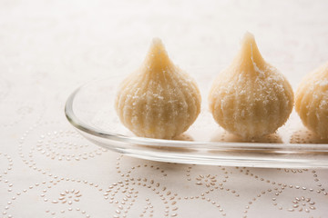 Sweet Modak made using coconut, khoya and sugar. Popular Maharashtrian recipe offered to lord Ganesha in Ganesh Festival. Served in a plate. Selective focus