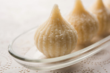 Sweet Modak made using coconut, khoya and sugar. Popular Maharashtrian recipe offered to lord Ganesha in Ganesh Festival. Served in a plate. Selective focus