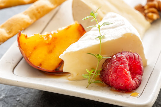Slice camembert cheese with grilled peach, fresh raspberries and fresh thyme, close up