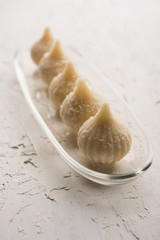 Sweet Modak made using coconut, khoya and sugar. Popular Maharashtrian recipe offered to lord Ganesha in Ganesh Festival. Served in a plate. Selective focus