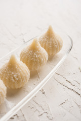 Sweet Modak made using coconut, khoya and sugar. Popular Maharashtrian recipe offered to lord Ganesha in Ganesh Festival. Served in a plate. Selective focus