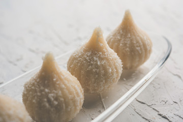 Sweet Modak made using coconut, khoya and sugar. Popular Maharashtrian recipe offered to lord Ganesha in Ganesh Festival. Served in a plate. Selective focus