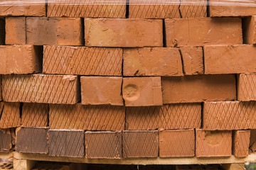Stack of red brick for construction. Common quality building bricks stacked ready for use.